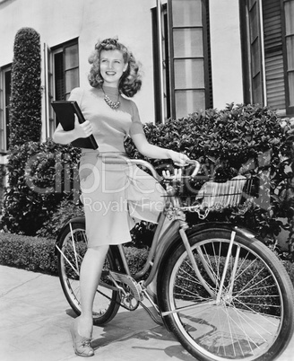 Woman sitting on her bicycle with a book in her arms