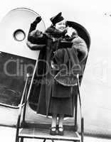 Elegant woman stepping out of an airplane and waving