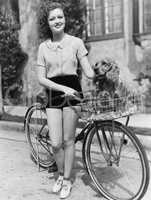 Woman next to her bicycle with her dog in the basket