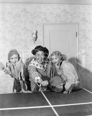 Two women and one man in a costume playing table tennis