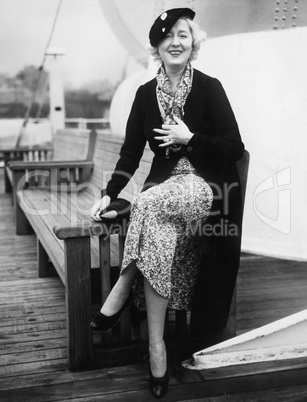 Woman sitting on the side of a bench on a ship