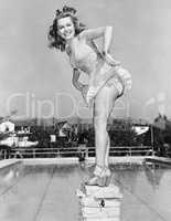 Woman posing on top of a pillar next to a swimming pool