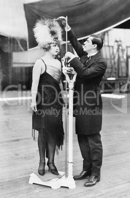 Man taking a measurement of a woman with an oversized hat
