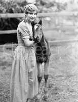 Woman standing next to a pony in a corral