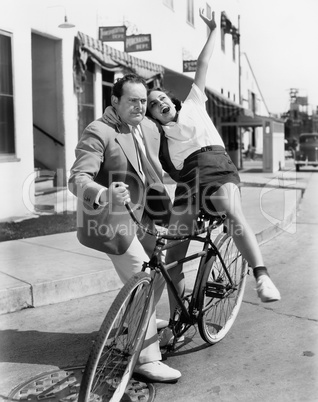 Man trying to balance an exuberant woman on a bicycle