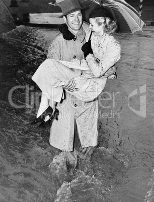 Young man carrying a woman through a rainstorm