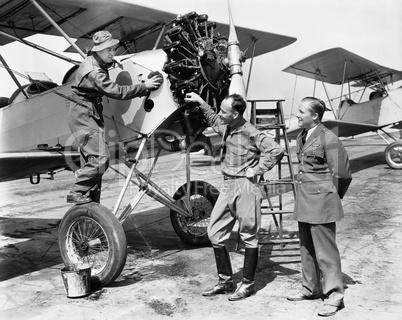 Three men standing next to an aircraft having a conversation