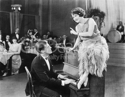 Young woman sitting on top a the piano and talking with the pianist