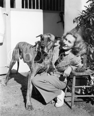 Woman bending next to her Great Dane to give him a hug