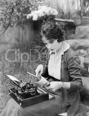 Woman sitting in the yard with a typewriter on her lap