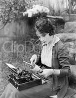 Woman sitting in the yard with a typewriter on her lap