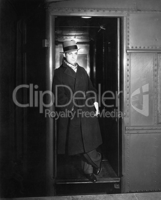 Man standing in the doorway of a train waiting