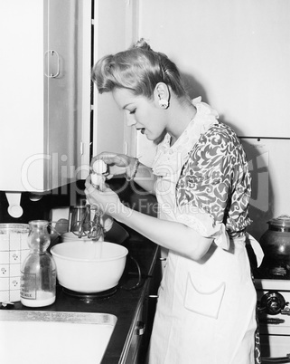 Woman in the kitchen cracking an egg