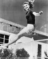 Woman leaping over a tennis net