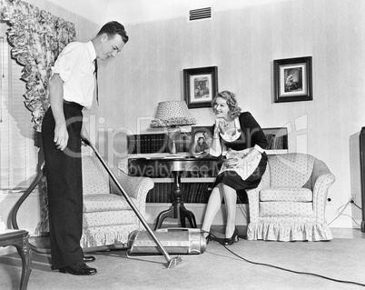 Salesperson demonstrates a vacuum cleaner to a housewife in her home