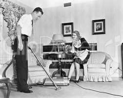 Salesperson demonstrates a vacuum cleaner to a housewife in her home