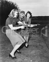 Two young women and a soldier trying out a machine gun