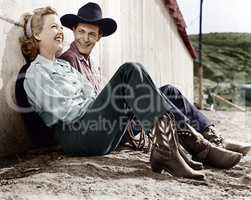 Laughing couple in western attire sitting on the ground