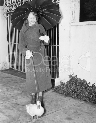 Woman walking in the rain with a duck on a leash