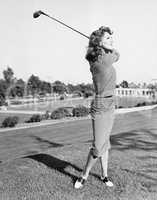 Woman on the driving range swinging a golf club