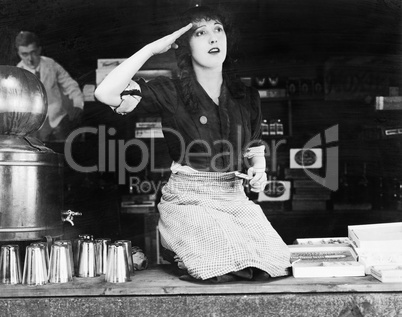 Woman kneeling on the counter of a bar and saluting