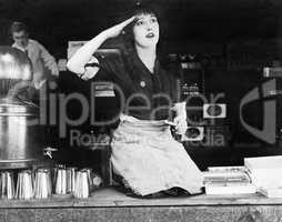 Woman kneeling on the counter of a bar and saluting