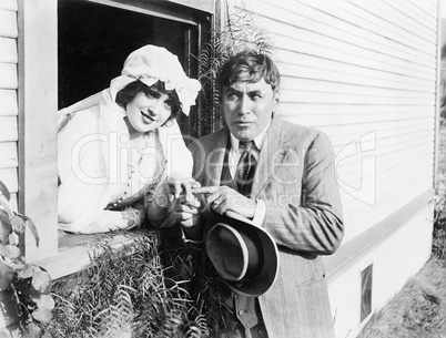 Married woman leaning out of a window to her husband