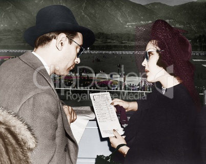 Elegant couple at a horse race looking at a program