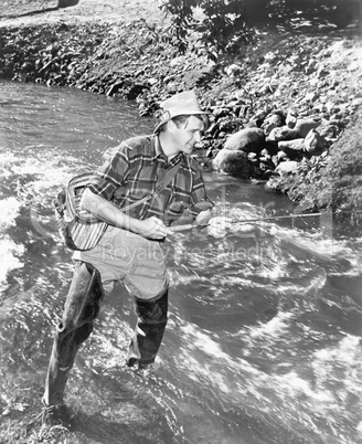 Man standing in a stream of water fishing