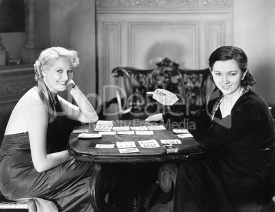 Two women sitting together playing cards