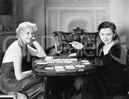 Two women sitting together playing cards