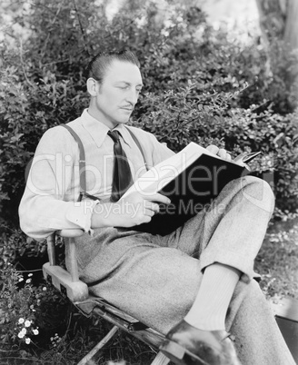 Man sitting in his garden reading a book