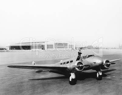 Woman standing on the propeller of an airplane waving