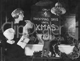 Woman reading sign with number of shopping days until Christmas