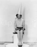 Portrait of woman with April Fool sign wearing dunce cap