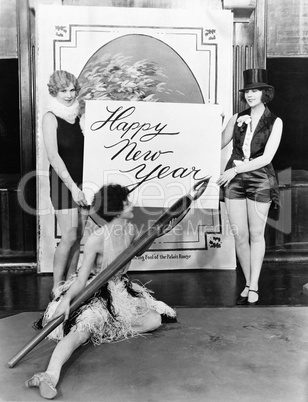 Women writing Happy New Year with huge pen