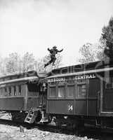Man leaping across the roof of railroad cars