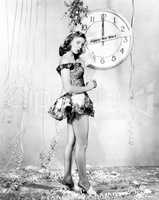 Young woman standing in front of a clock, celebrating New Years Eve