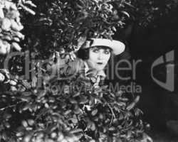 Woman peeking through bushes
