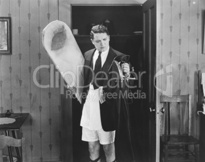 Man in boxer shorts holding iron and ironing board