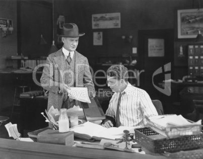 Man with attitude showing papers to office worker