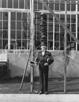 Man standing with stack of hats on head