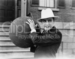 Man in hat holding large ball