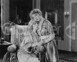 Young woman consoling her friend in wheelchair