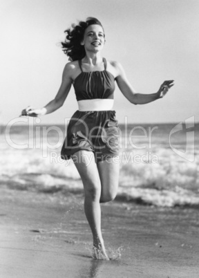 Cheerful young woman running on beach