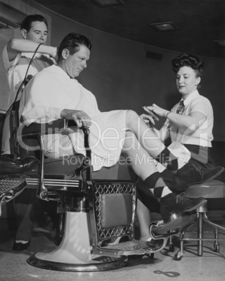 Man getting his hair cut and nails manicured