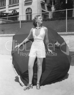 Woman standing in front of beach umbrella on beach