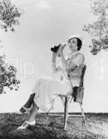 Elegant woman sitting on chair while holding binoculars