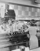 Rear view of smiling woman pouring drink from soda fountain