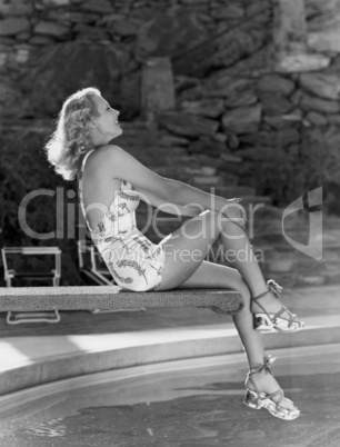 Smiling woman sitting on edge of diving board